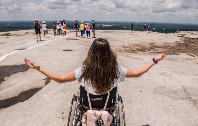 An adolescent, who uses a wheelchair, views the Appalachian Mountains from the top of Stone Mountain.